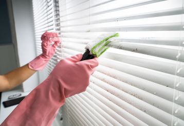 Cleaning vinyl blinds with a sponge for a spotless finish.